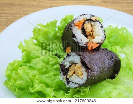 Japanese Cuisine Traditional Vagetarian Japanese Rice Maki Sushi Roll Stuff with Tofu and Carrot Wrapped in Nori Seaweed Served on Green Oak.