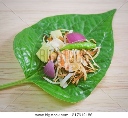Thai Traditional Snack and Dessert Dish of Miang Kum or Sweet and Spicy Betel Leaf Wrap Filled with Coconut Peanuts Dried Shrimp Chiles and Lime.