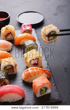 Eating sushi at restaurant. Chopstick taking roll with eel shavings, japanese cuisine, copy space