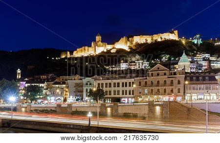 Amazing night view of Olt town with Narikala ancient fortress and the embankment with blurred lights of traffic , St Nicholas Church in night Illumination, Tbilisi, Georgia.