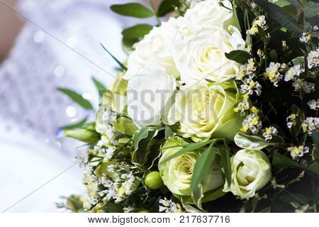 Beautiful wedding bunch with different flowers selective focus and blurred wedding dress background