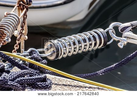 Metal cleat for mooring boats, bolted to the ground, with rope and shock absorber spring .