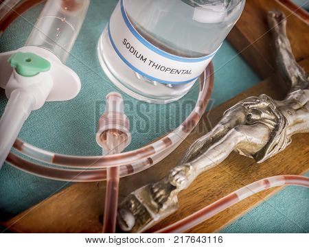 Wooden crucifix and metal next to a vial containing sodium thiopental anesthesia used in capital punishment and euthanasia, conceptual image