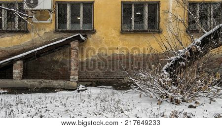 Old apartment block. Old building fragment. Yellow house. Entrance to the basement