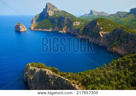 View from height to the blue bay in rocks with green forest of pines