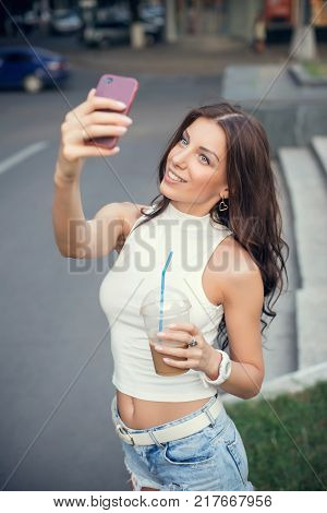 Beautiful, sexy girl taking a selfie in the street.