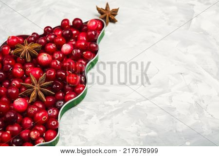 Christmas tree of cranberry and star anise over gray background with copy space