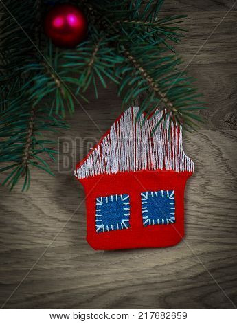 concept of Christmas.knitted house and pine branch on wooden background. place for text
