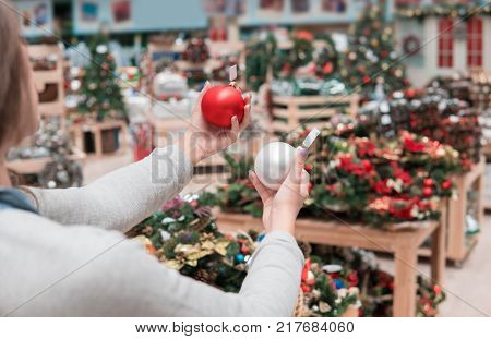 happy customer girl choosing Christmas tree decoration balls. difficult decision. Various choice