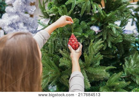 Cheerful happy customer girl choosing Christmas tree decoration balls. difficult decision. Various choice