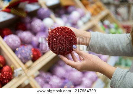 Cheerful happy customer girl choosing Christmas tree decoration balls. difficult decision. Various choice