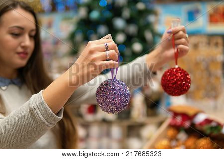 happy customer girl choosing Christmas tree decoration balls. difficult decision. Various choice