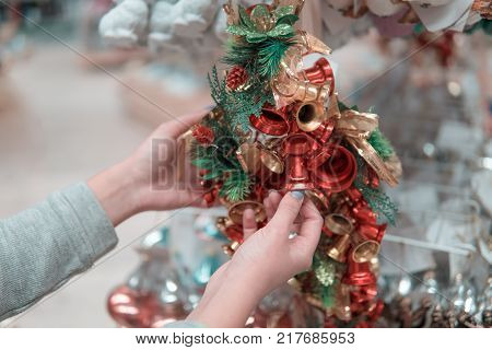 Cheerful happy customer girl choosing Christmas tree or New Year's decoration bells