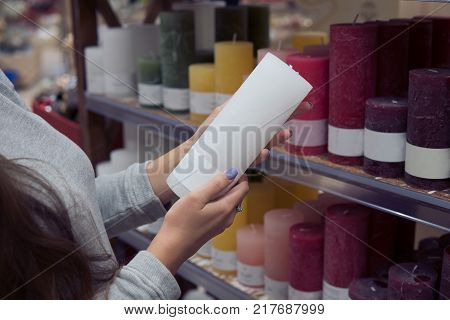 Closeup view of woman hands choosing white festive decorative candles for Christmas or New Year celebration