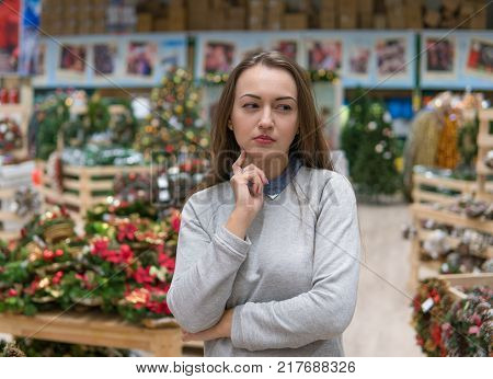 girl choosing gifts for Christmas and New Year. she is at a loss from the variety of goods. she is thinking