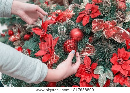 Closeup view of hands decorating Christmas tree with decoration balls. Beautiful holiday decoration.