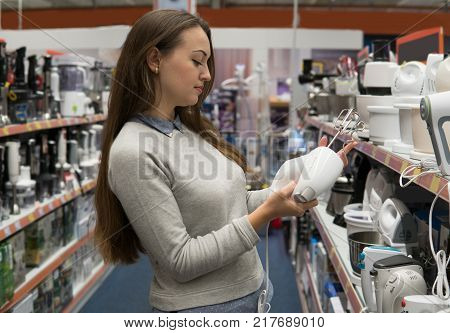 Smart female customer girl chooses a mixer or blender in a home appliance store. difficult decision. Various choice