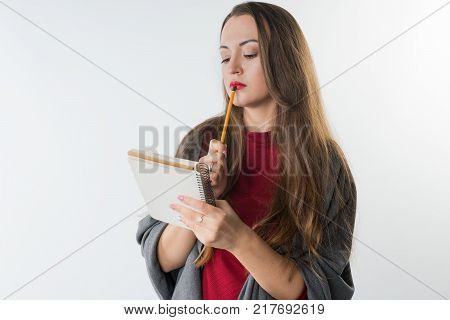 young caucasian female with sketchbook and pencil on white background. She is thinking