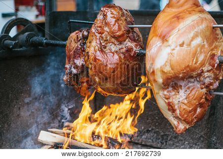 Large chunks of delicious pork hams cooked on an open fire. The street food. Food outdoors. Camping and cooking on a spit over the fire. Camping.