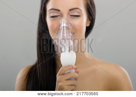 The inhalation young woman keeping inhale mask