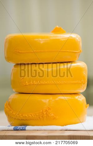 Three big organic cheese heads in yellow vacuum package laying on top of each other in the farm kitchen.. Food concept