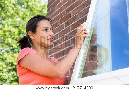 Colombian woman working sanding window of house outside
