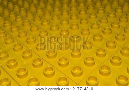 Abstract shapes and textures: A sea of yellow plastic building bricks all ligned up as far as they eye can see.