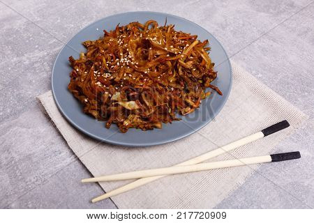 A top view on a chinese food. Chopsticks and Chinese spicy sea kale with chilli and sause on the marble background. Close-up of objects. Food concept.