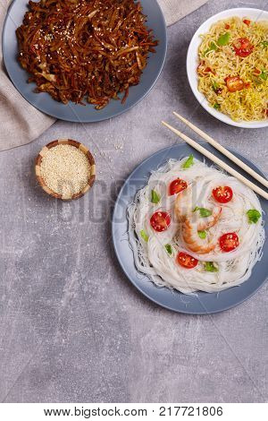 A top view on a chinese food. Chilli, mushrooms, shrimps on a rise noodles, tomatoes on Chinese spicy sea kale on the light blue marble background. Close-up of objects. Food concept.