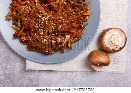 A top view on a chinese food. Chopsticks, Chinese spicy sea kale with chilli and mushrooms on the marble background. Close-up of objects. Food concept.