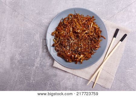 A top view on a chinese food. Chopsticks, Chinese spicy sea kale with chilli and mushrooms on the marble background. Close-up of objects. Food concept.