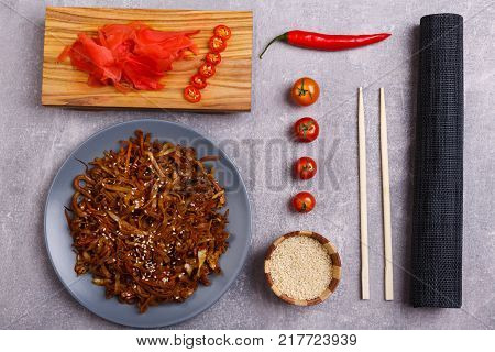 A top view on a chinese food. Chopsticks, Chinese spicy sea kale with chilli and sauce on the marble background. Close-up of objects. Food concept.