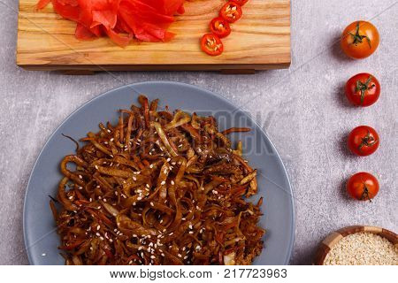 A top view on a chinese food. Chopsticks, Chinese spicy sea kale with chilli and sauce on the marble background. Close-up of objects. Food concept.