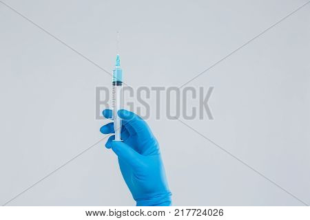 A top view on hand with syringe and medicine vial prepare for injection on the gray background. Close-up of object. Medical concept.
