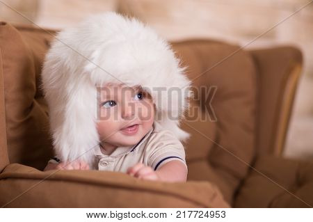 Happy Newborn Child Baby Boy With Pink Cheeks Posing On Hege Retro Casual Style Brown Couch Divan So