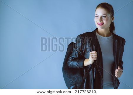 Portrait of beautiful young brunette woman in stylish black jacket on gray