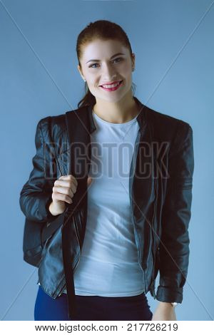 Portrait of beautiful young brunette woman in stylish black jacket on gray