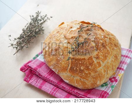 Round bread with thyme sprig upon rustic table. Homemade bread. Selective focus.