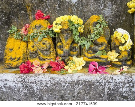 The stone sculptures of the nagas, deities to whom the celebration of installation is dedicated. The traditional decoration of murti of snake with flowers and yellow dust