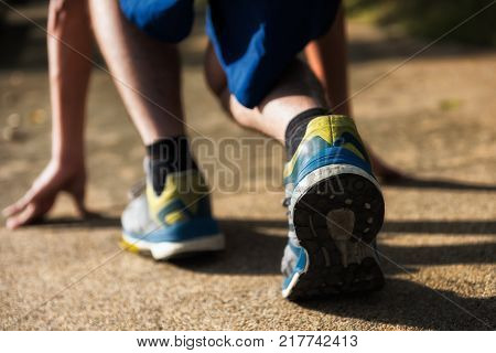 Closeup rear feet with running shoes of an athlete to start to run at the park with sunset light. Healthy lifesytle for working man to losing weight.