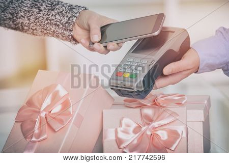 Making contactless payment for a gifts with smart phone over payment terminal at shop
