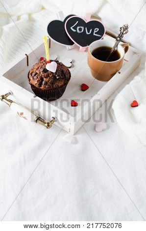 Muffins or capkakes with chocolate and black coffee on a wooden tray in bed. White background. Sweet food. Festive mood copy space flat lay