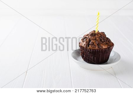 Birthday muffins or capkakes with chocolate and candle on a white wooden table. White background. Sweet food. Festive mood copy space flat lay