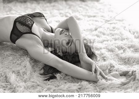 Sexy young passionate brunette woman in bra posing on carpet black and white