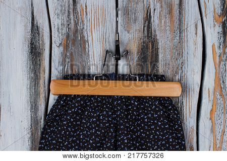 Black pants on wooden hanger. Garment with girlish floral pattern. Girls' clothing apparel for lounging at home.