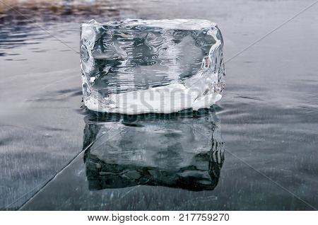 Single Ice Cube with reflection on the lake Baikal surface