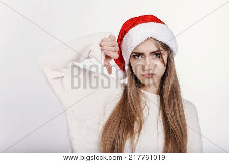 The Young Woman In Santa Hat Showing Thumbs Down And Make Capricious Face