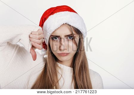 The Young Woman In Santa Hat Showing Thumbs Down And Make Capricious Face