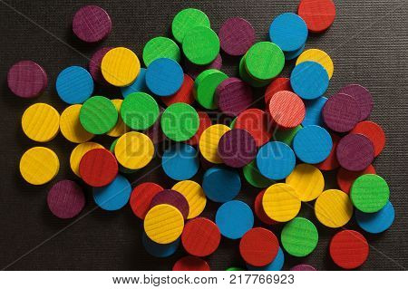 Round, wooden, multicolored, game chips on a black textured background