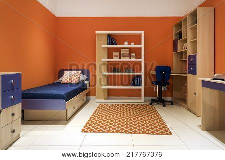 Shot of a modern colorful children's room. Room for the teenager with a small bed with blue linens. In the room, wardrobes, tables, computer Desk